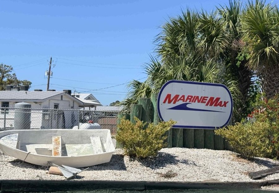 The MarineMax sign with a small decorative boat at the Savannah Bend Marina entrance on Old Tybee Road