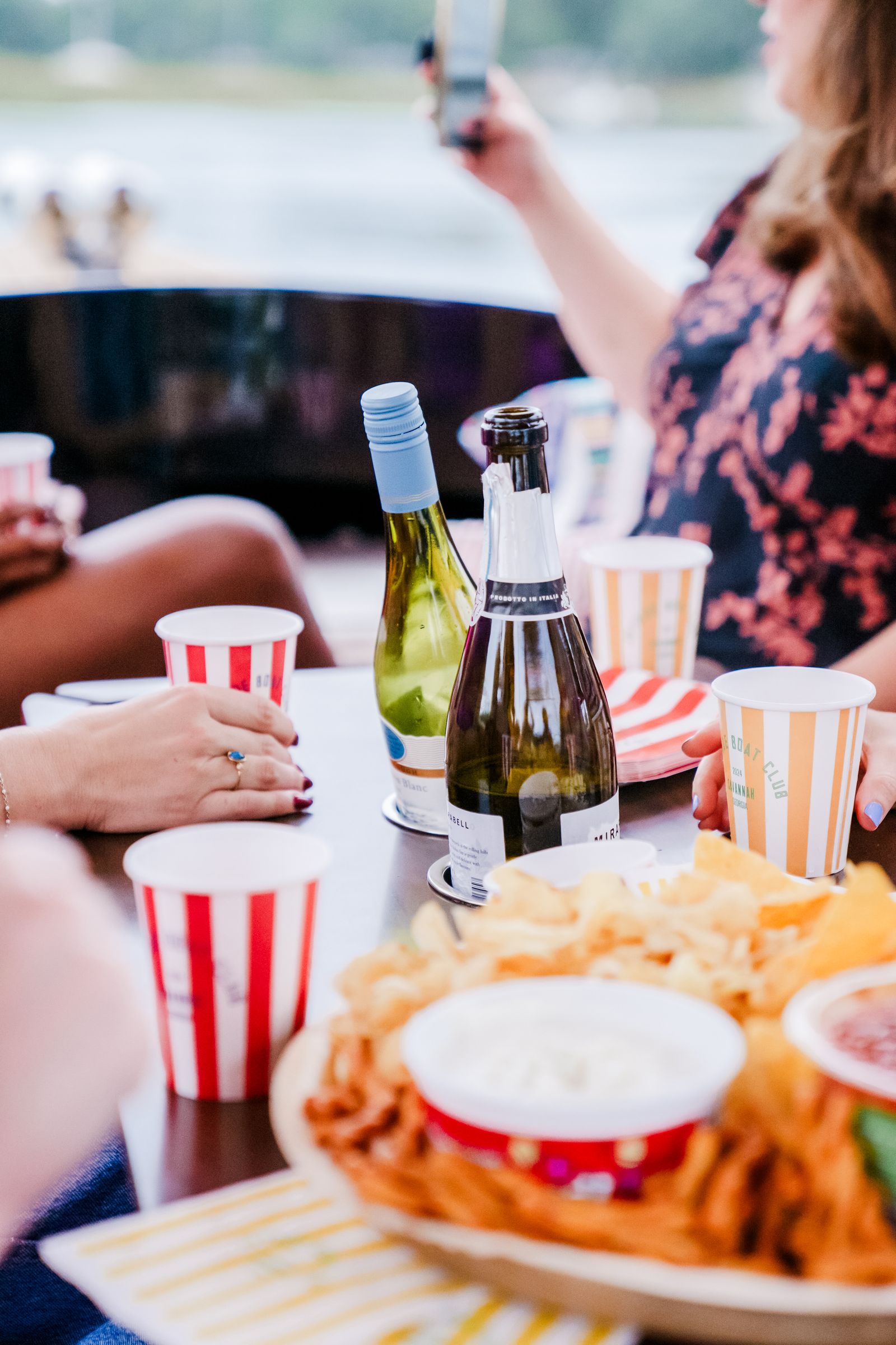 Red-striped Joyride Boat Club cups with wine and snacks on the boat's center table