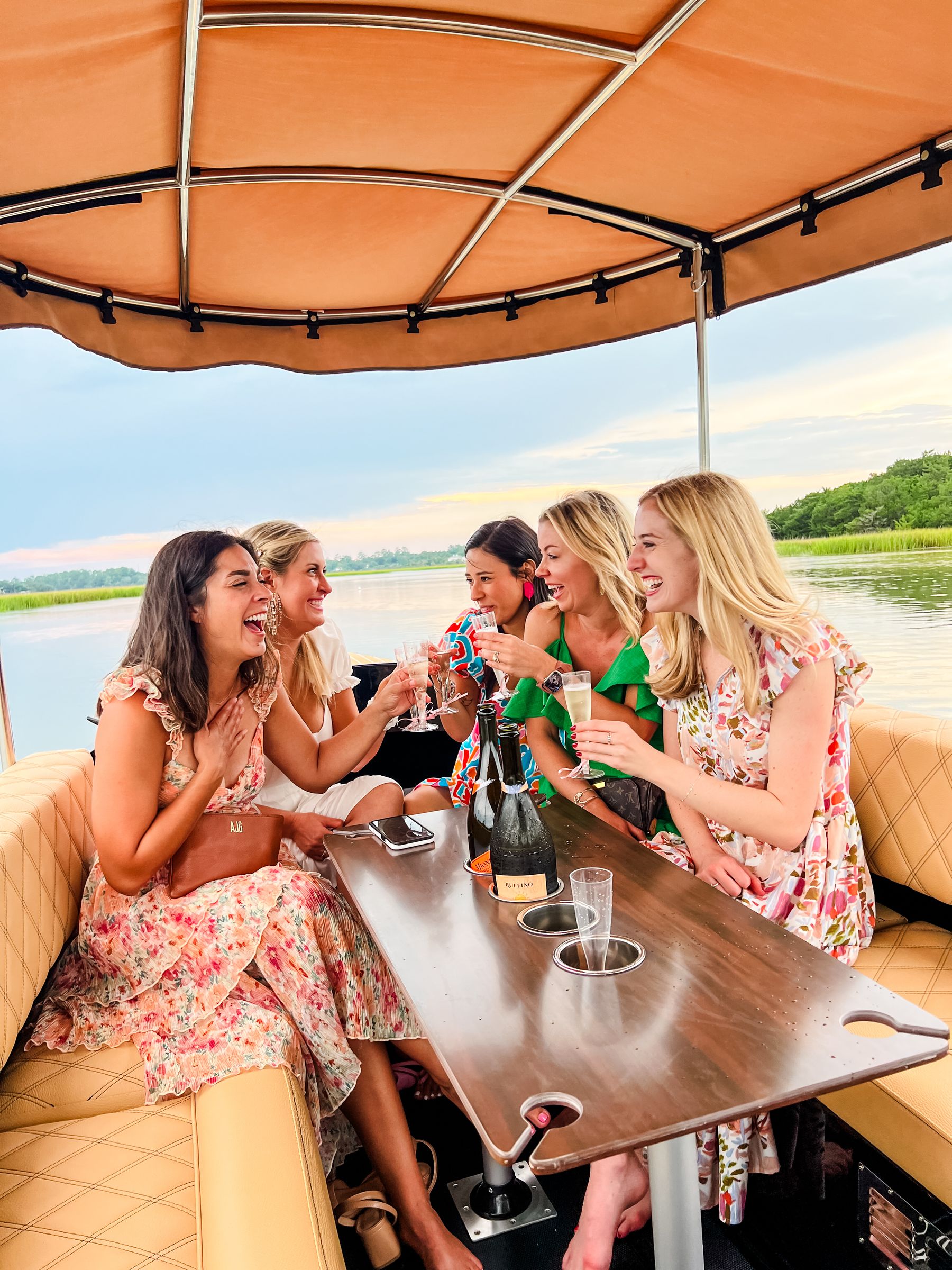 Five friends raising a champagne toast at sunset on the Joyride boat in the Savannah marsh