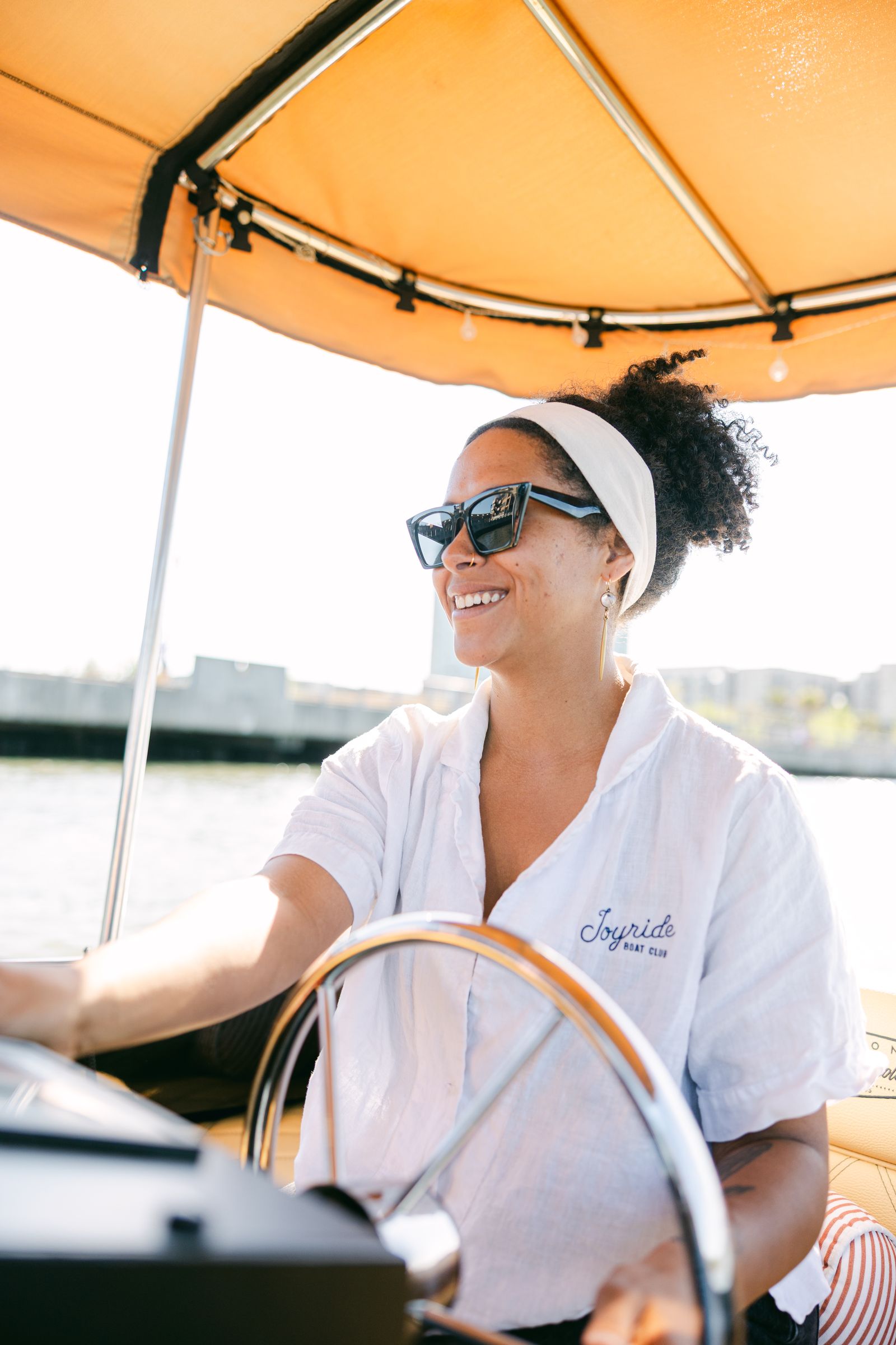 Captain Taryn at the helm in an embroidered Joyride Boat Club linen shirt