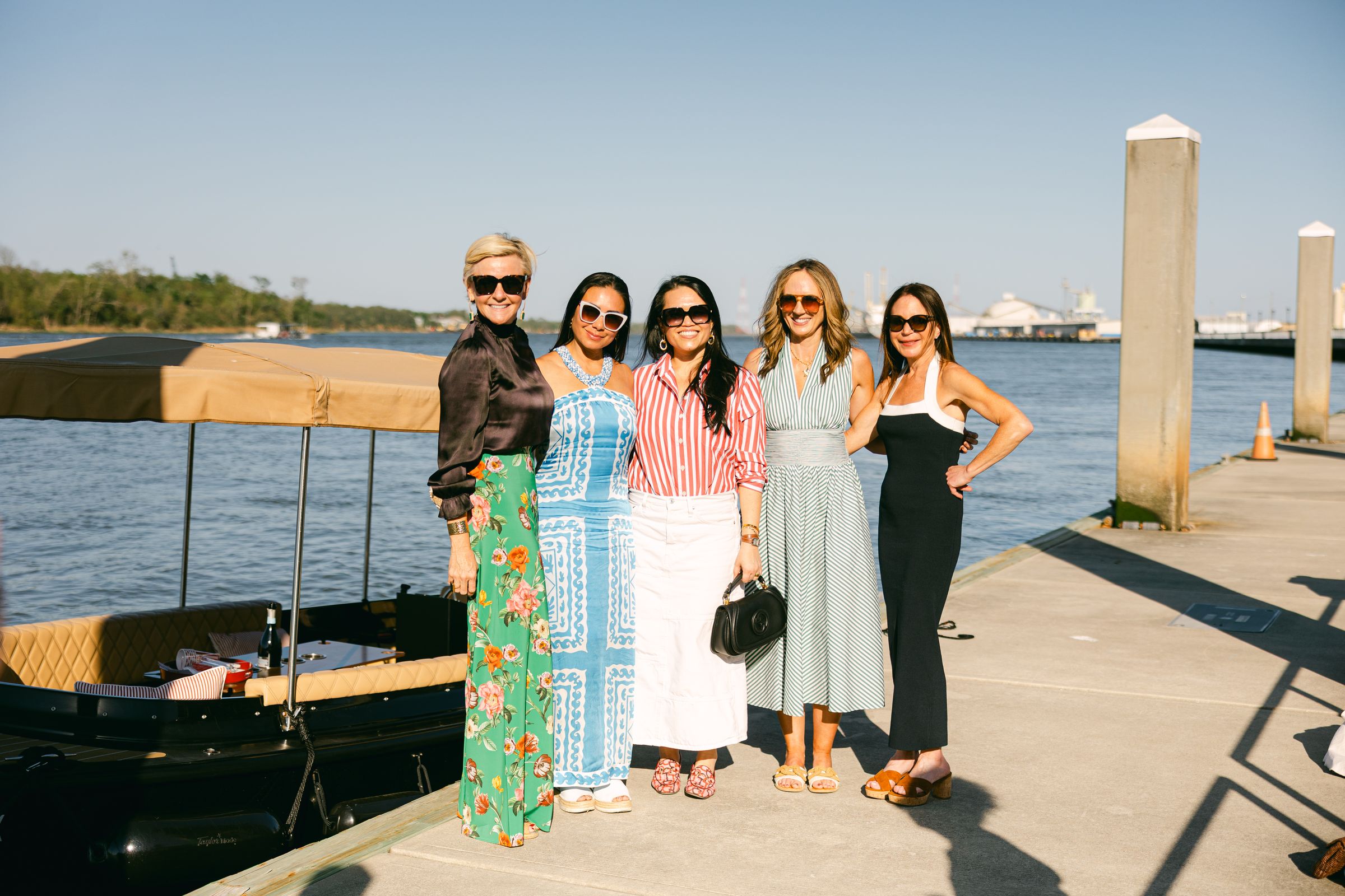 Five guests posed on the dock beside the Joyride boat before a hosted event