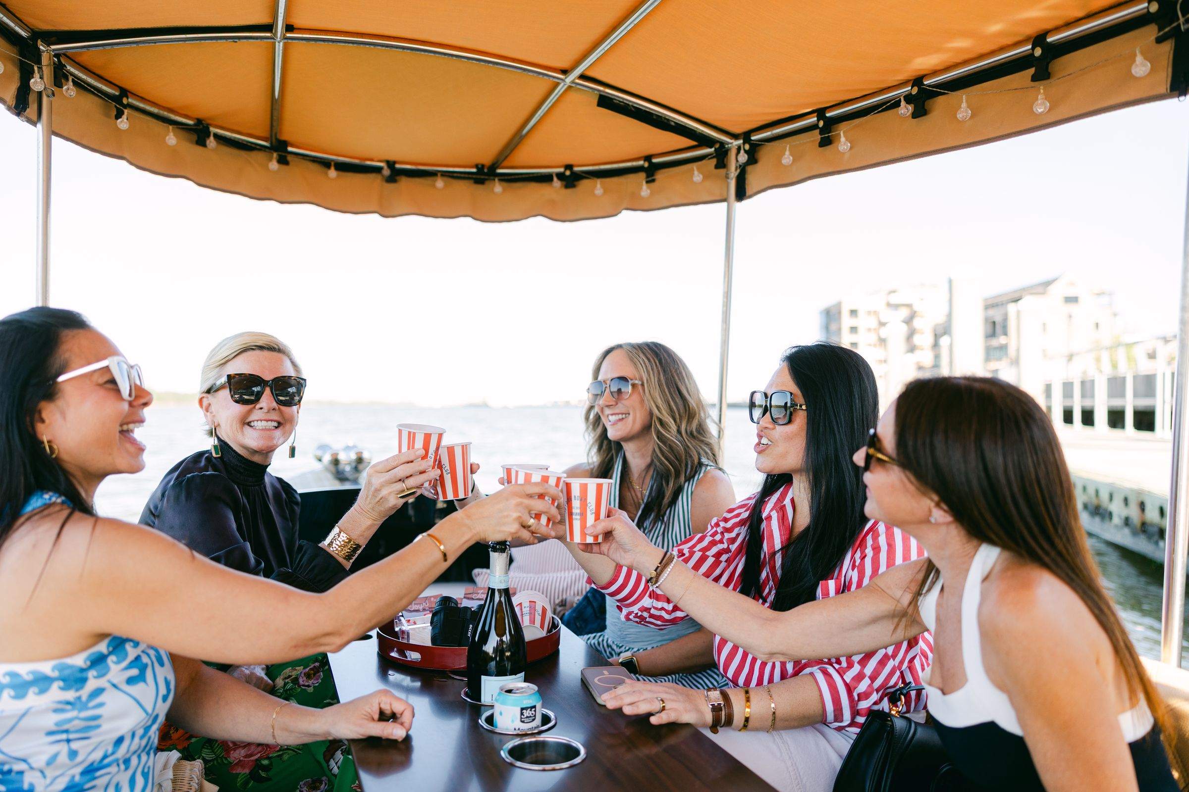 A group of women toasting under the Joyride canopy during a hosted event on the Savannah River