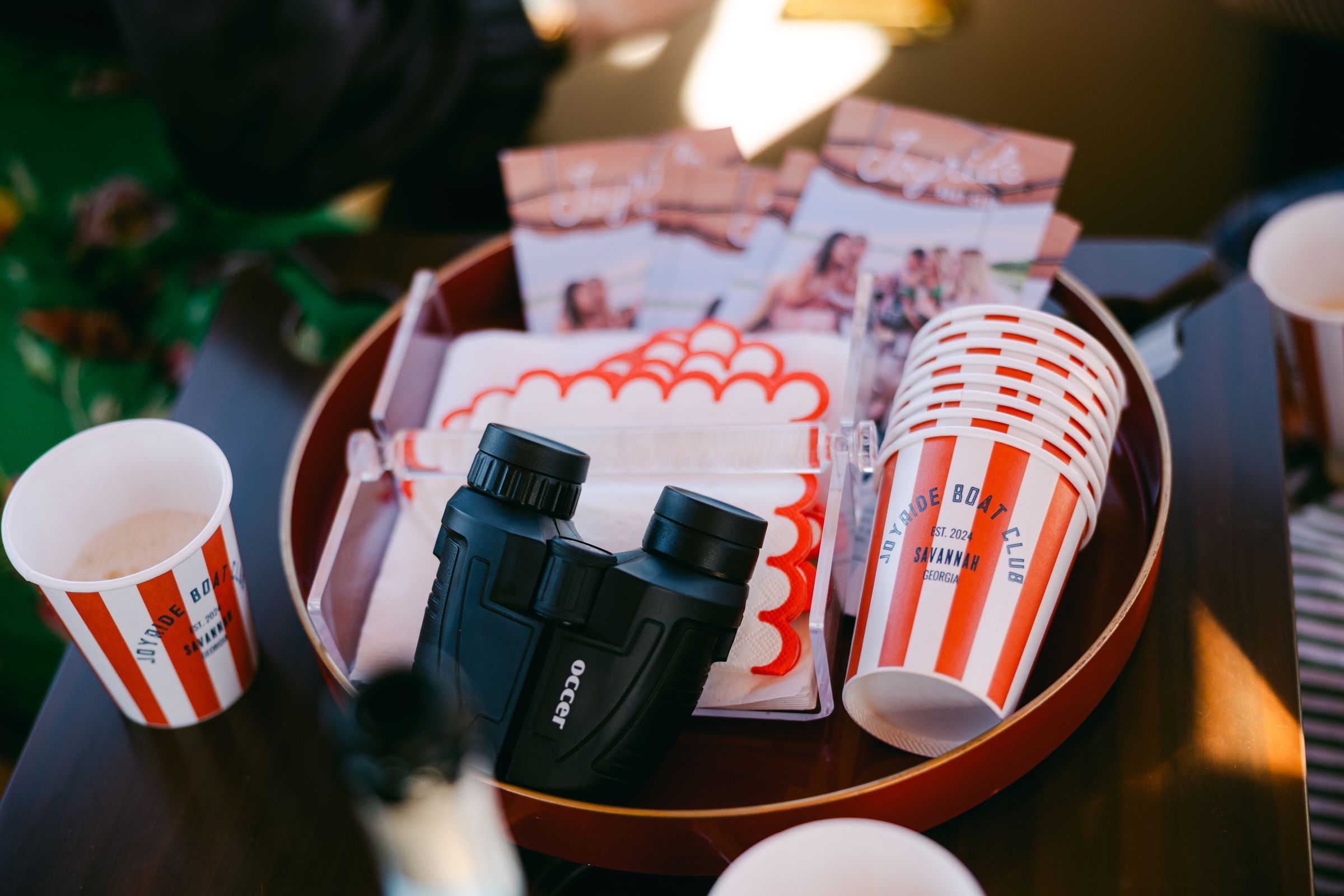 A hosting tray with binoculars, Joyride branded cups and scalloped napkins