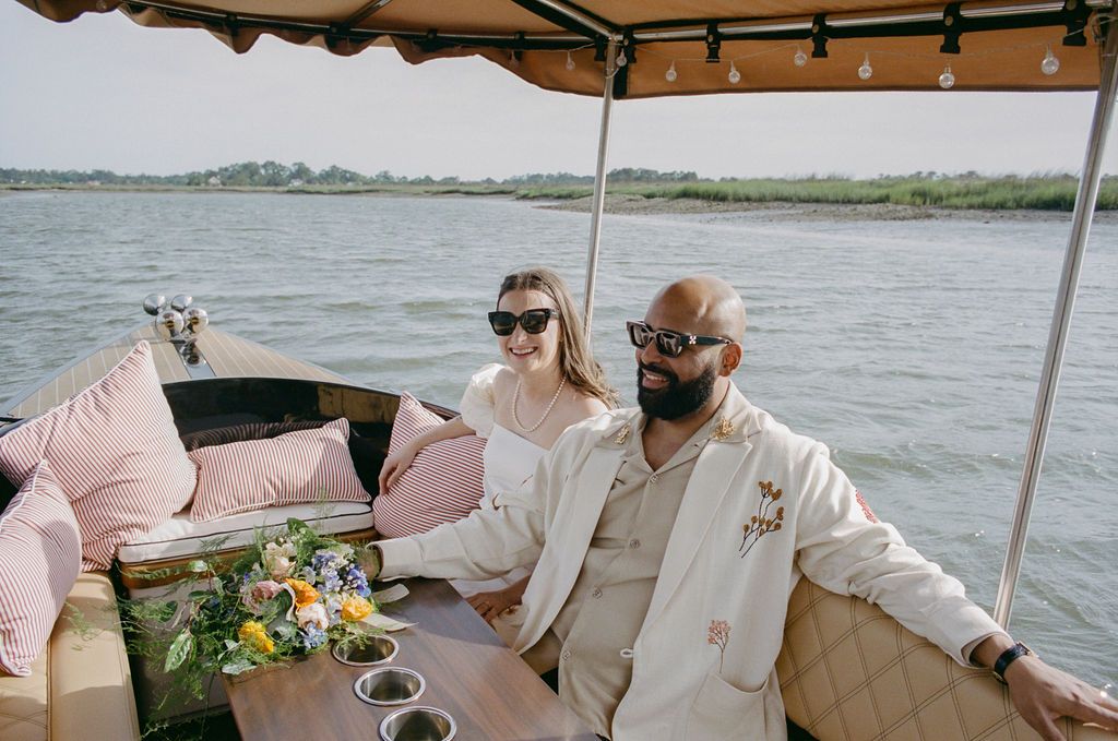 Newlyweds seated on the Joyride boat with a bouquet on the table, marsh behind