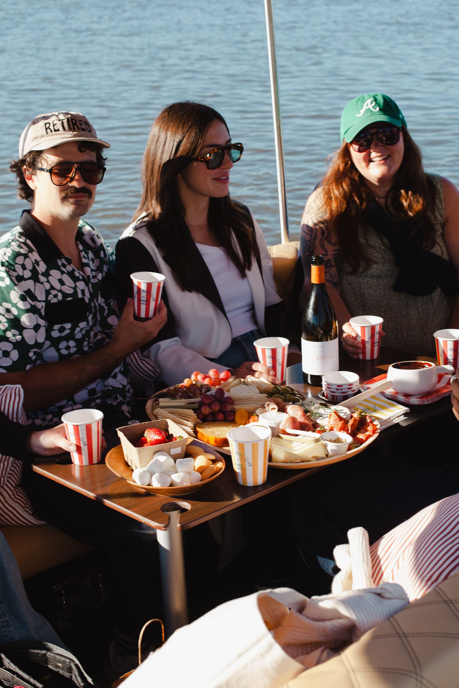 Three guests at the Joyride table with a Provisions charcuterie spread and wine, water behind
