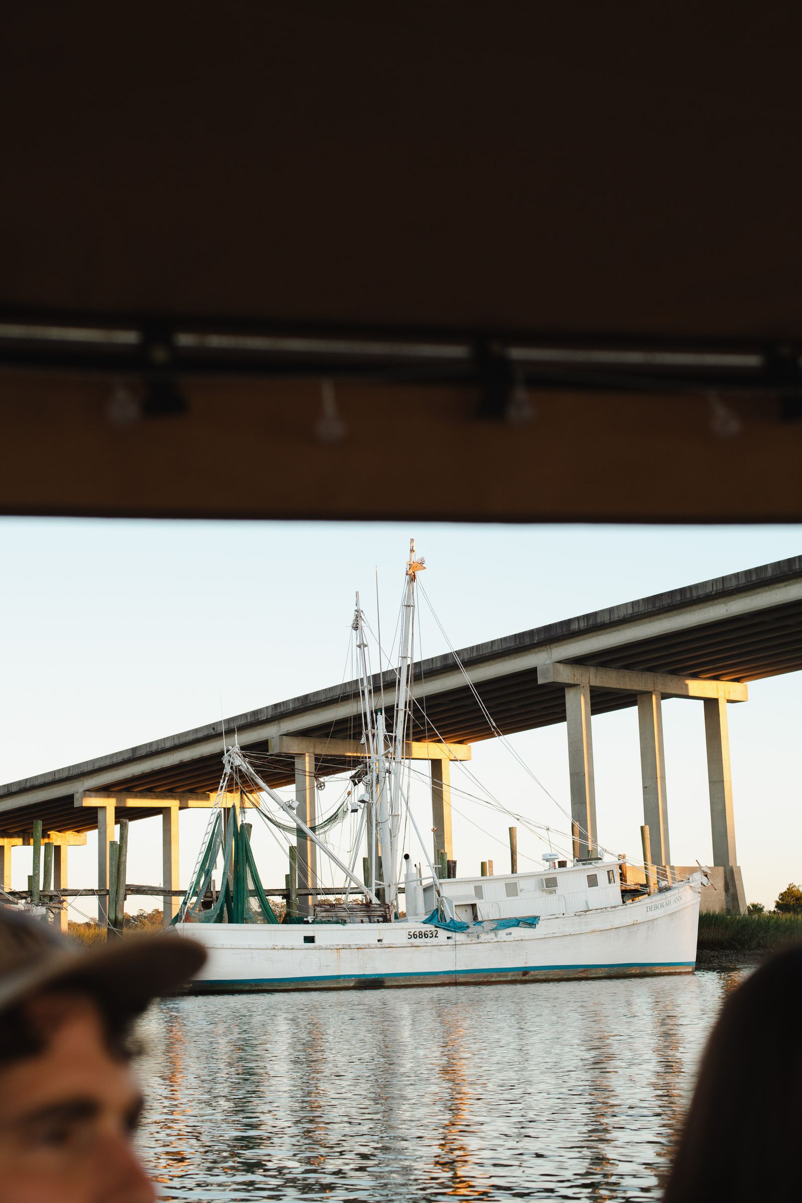 A shrimp boat passing under the Thunderbolt bridge, framed by the Joyride canopy