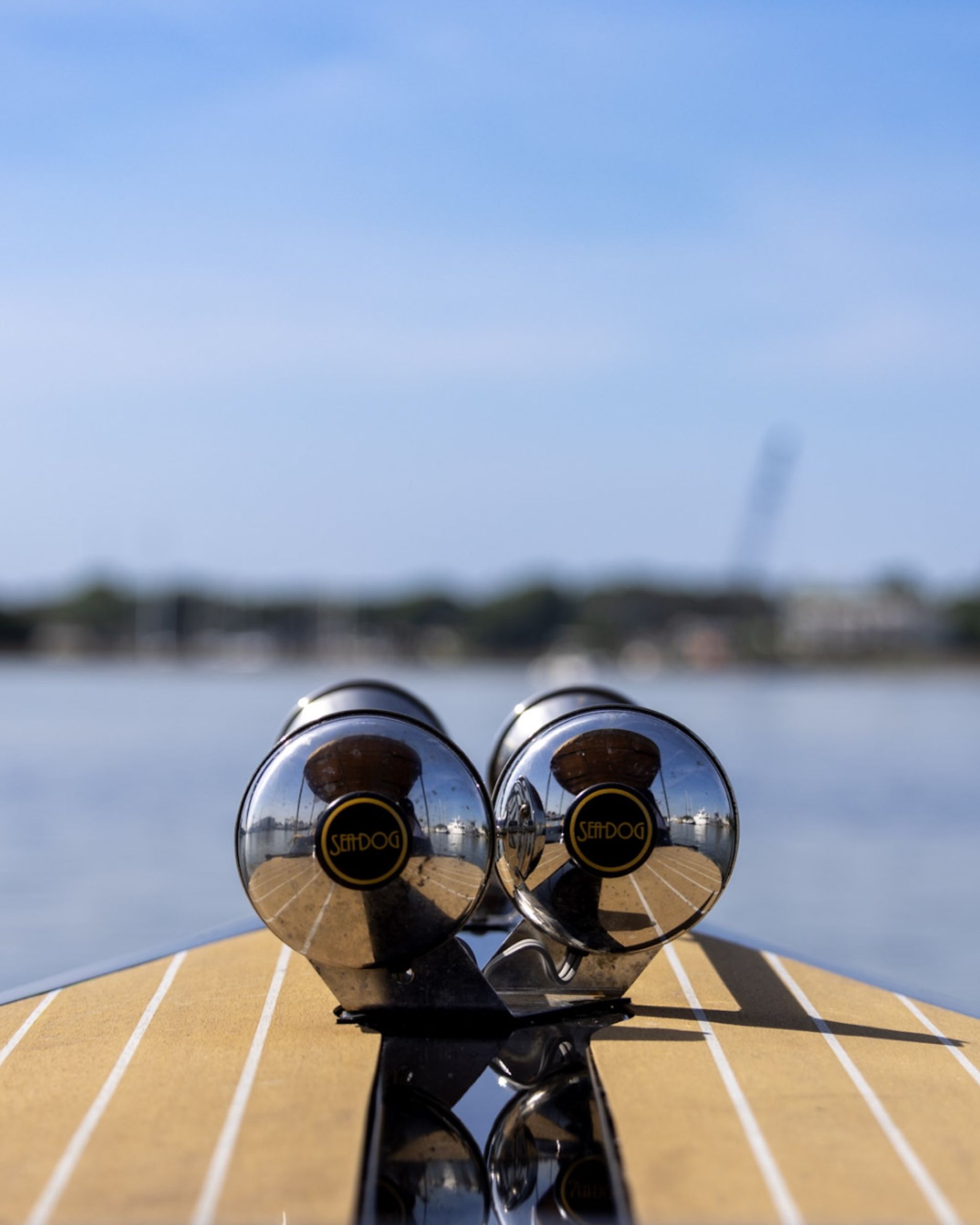 Polished chrome horns on the teak bow of the Joyride boat, marina reflected in the chrome
