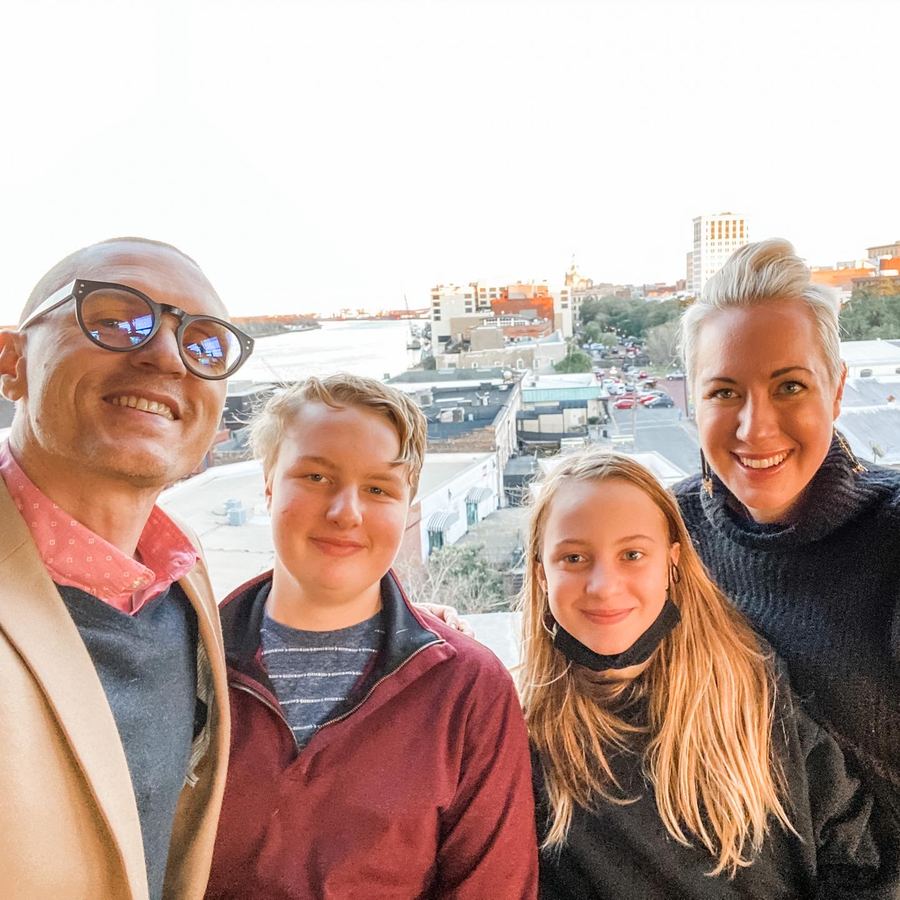 Audra, Justin and their two kids on a rooftop overlooking downtown Savannah and the river