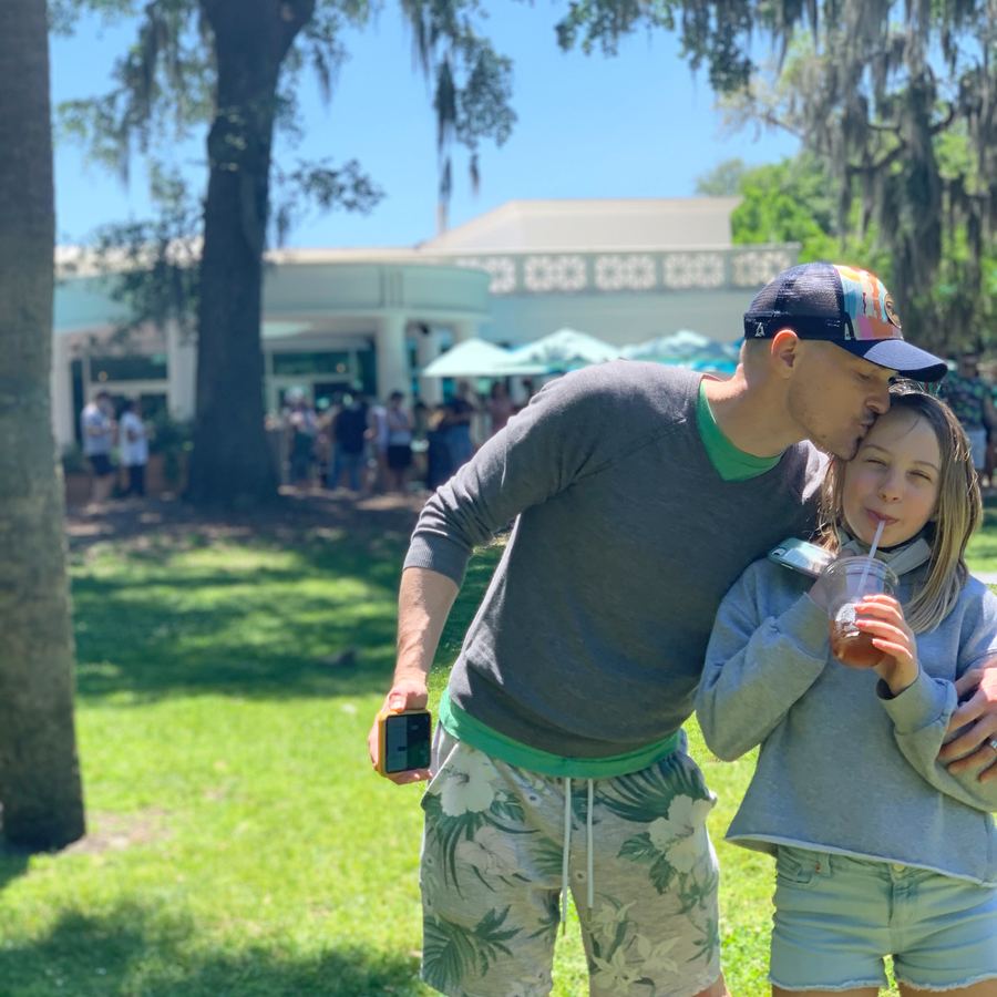 Justin kissing their daughter's head in Forsyth Park under the live oaks