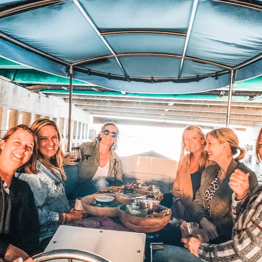 Friends cruising under a bridge on an electric boat in Newport Beach