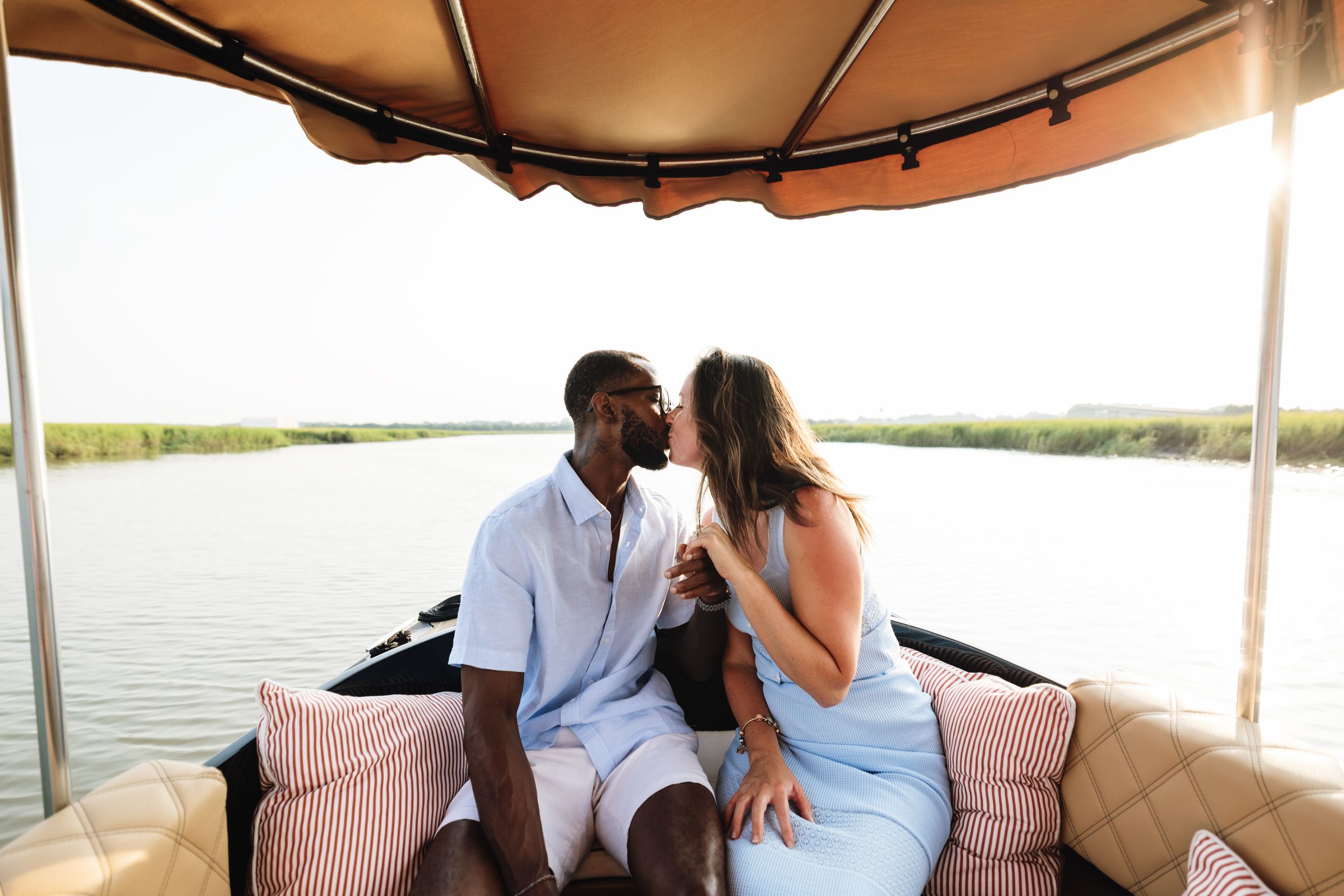 A newly engaged couple kissing under the Joyride canopy, marsh stretching ahead