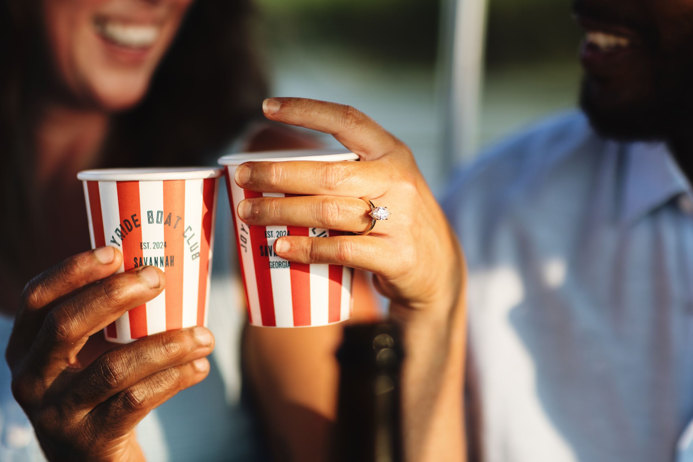 Close-up toast with Joyride Boat Club cups and an engagement ring
